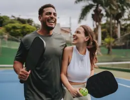 a man and a woman holding paddles on a pickleball court